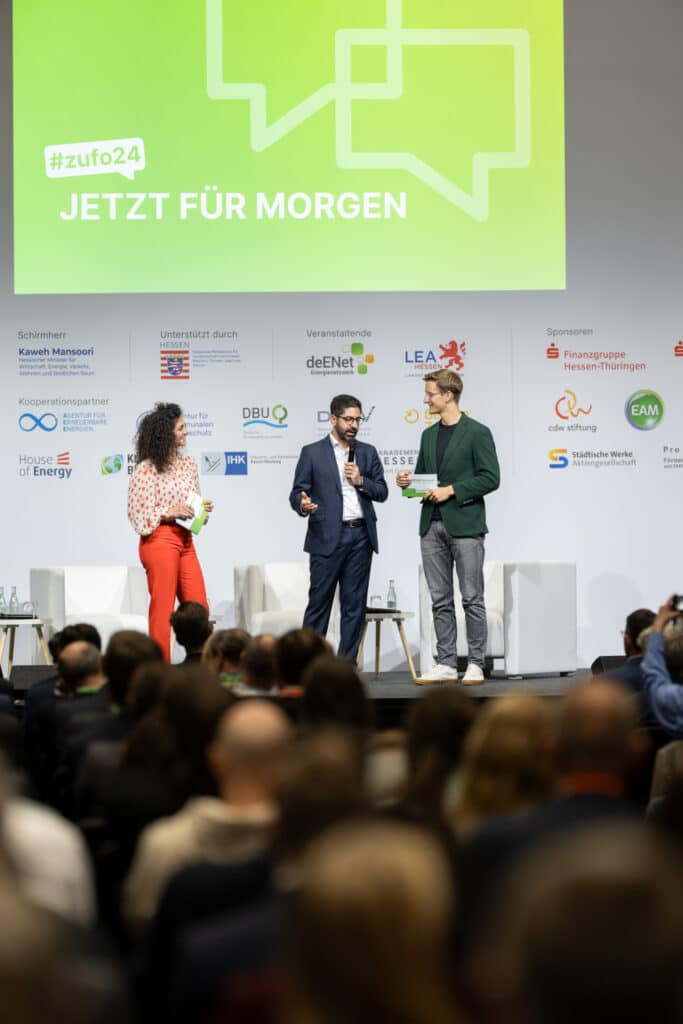 Nachhaltigkeitsmoderator interviewt Minister Kaweh Mansoori bei einem Event.