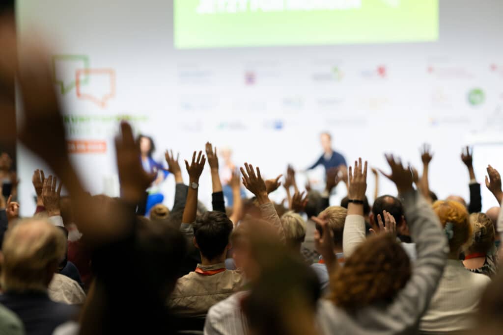 Menschen heben die Hände bei einer Konferenz